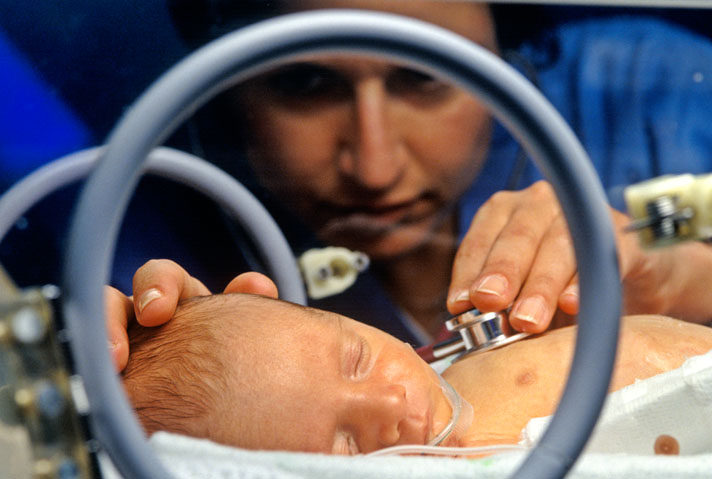 A68GRN Nurse attends premature infant in an incubator in neonatal intensive care unit NICU